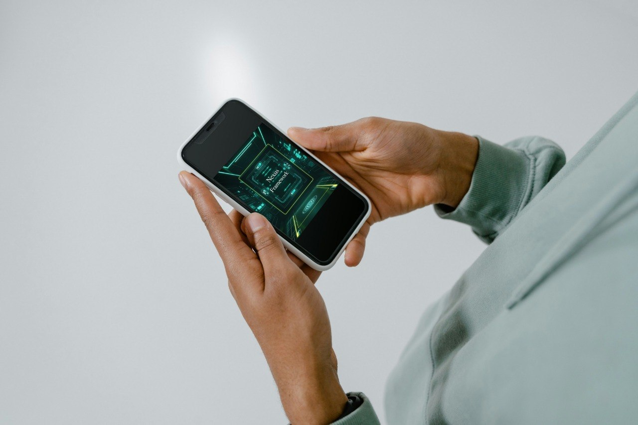 Person holding a smartphone with a green digital interface on a plain background